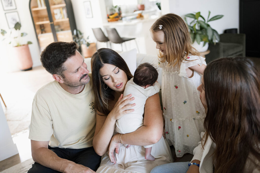 The Robbins family snuggles newborn Rowan on their living room couch during an in-home newborn family session after a home birth.