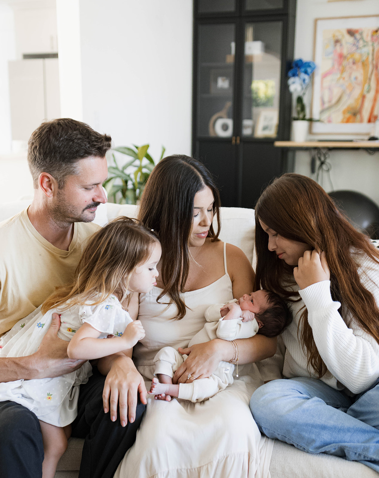 The Robbins family snuggles newborn Rowan on their living room couch during an in-home newborn family session after a home birth.