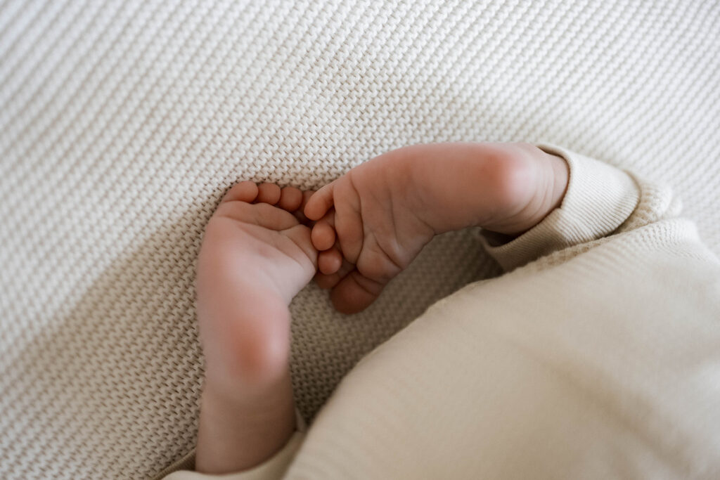 Newborn Rowan peacefully sleeps in a neutral clothes during an in-home family session, photographed in the space where he was born.