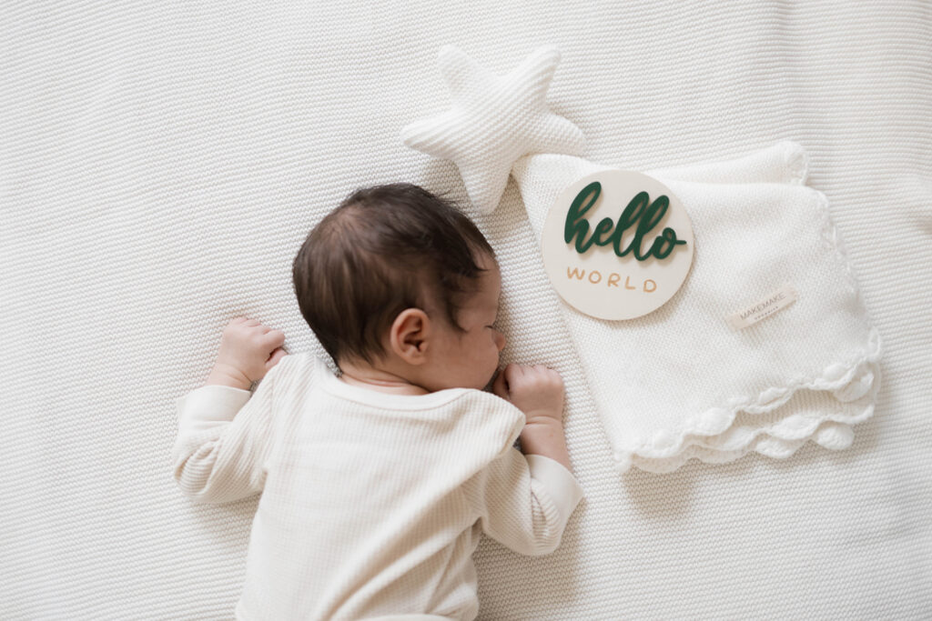 Newborn Rowan peacefully sleeps in a neutral clothes during an in-home family session, photographed in the space where he was born.