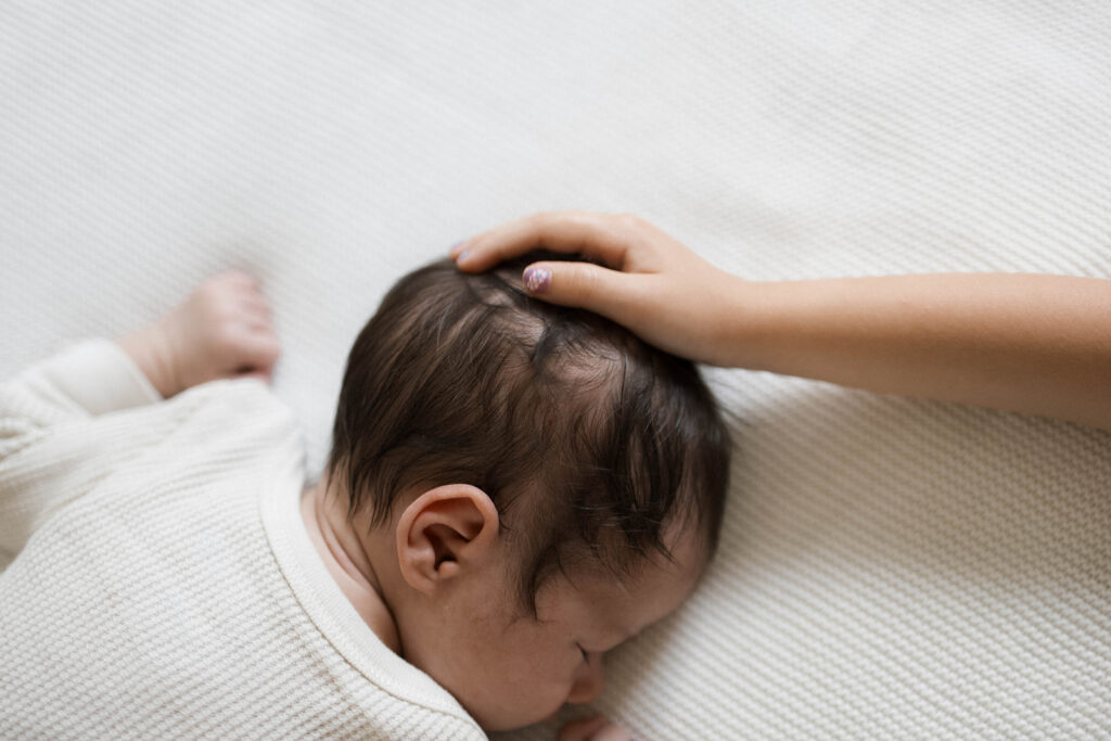 Newborn Rowan peacefully sleeps in a neutral clothes during an in-home family session, photographed in the space where he was born.