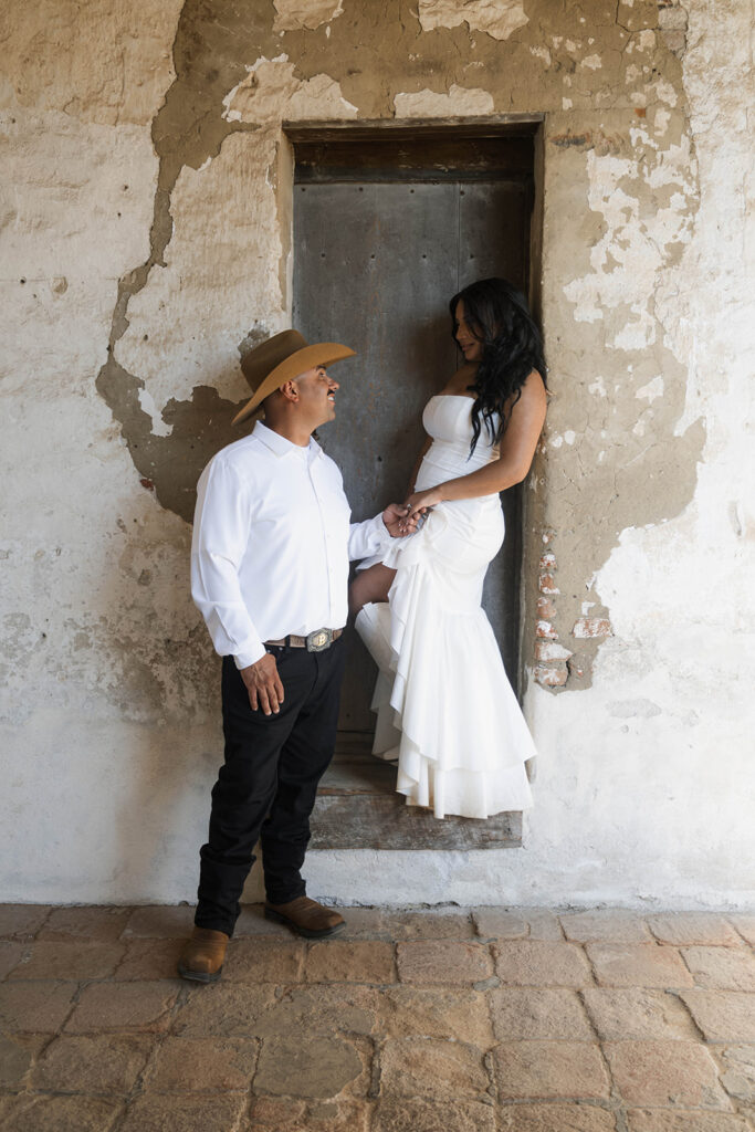 future bride and groom taking western style engagment photos at san juan capistrano mission