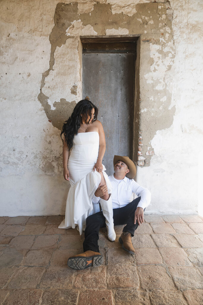 future bride and groom taking western style engagment photos at san juan capistrano mission