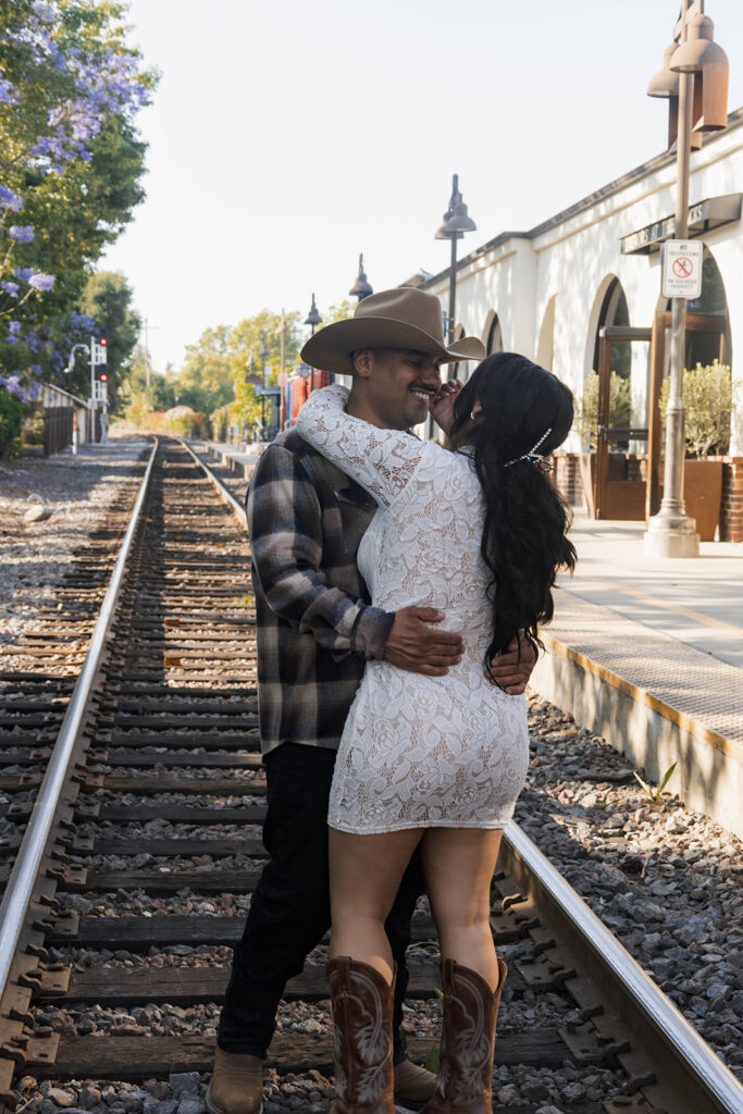 future bride and groom taking western style engagment photos at train tracks