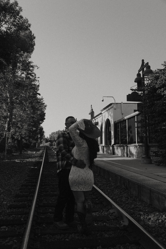 future bride and groom taking western style engagment photos at train tracks