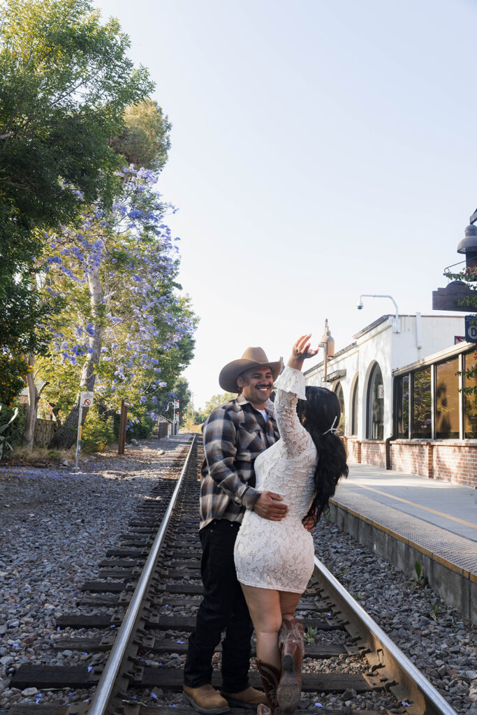 future bride and groom taking western style engagment photos at train tracks