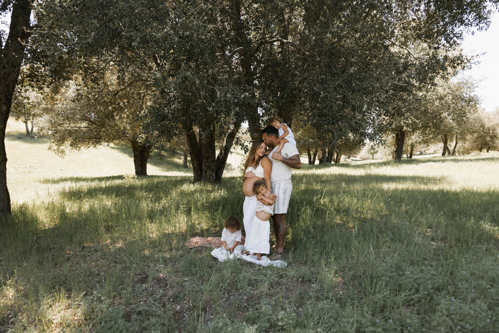 family of 5 in grassy field, mother is expecting 5th child.