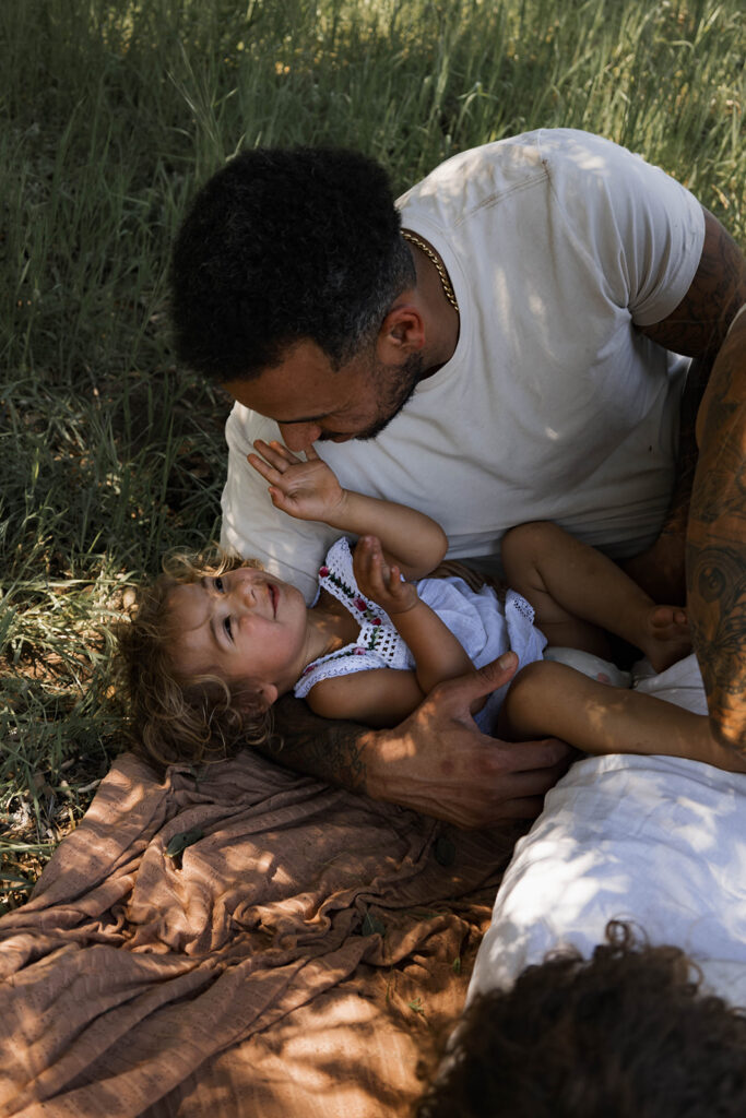 father and youngest daughter playful in the grass