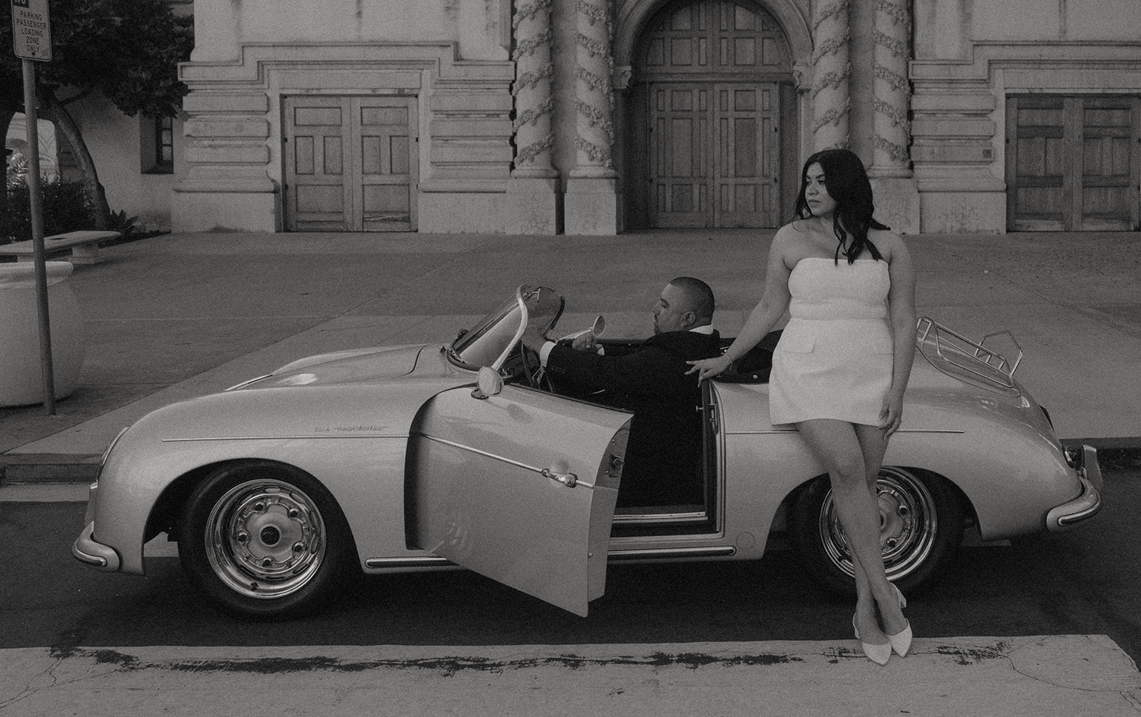Sabrina and Azor posing in front of a classic vintage car from SD Vintage Rides at Balboa Park, exuding formal glamour.
