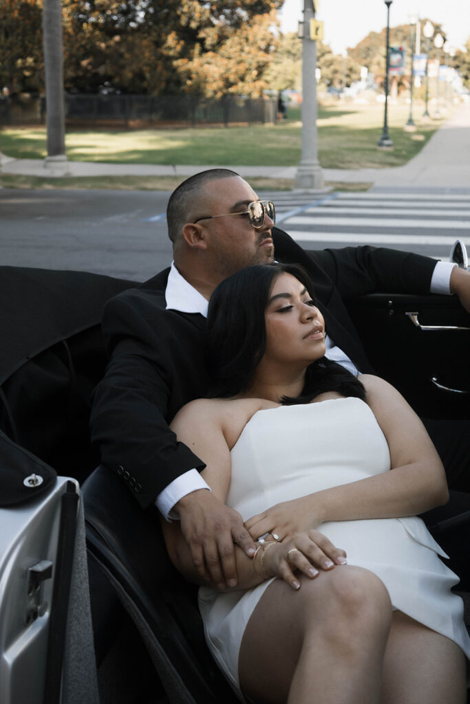 Sabrina and Azor posing in front of a classic vintage car from SD Vintage Rides at Balboa Park, exuding formal glamour.