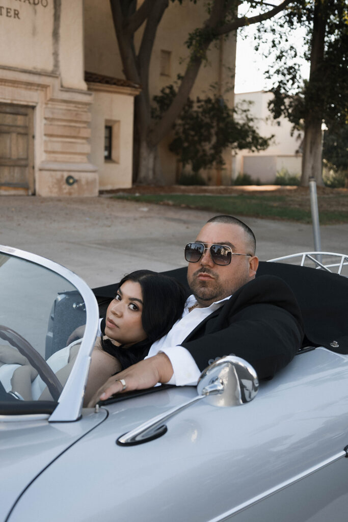 Sabrina and Azor posing in front of a classic vintage car from SD Vintage Rides at Balboa Park, exuding formal glamour.