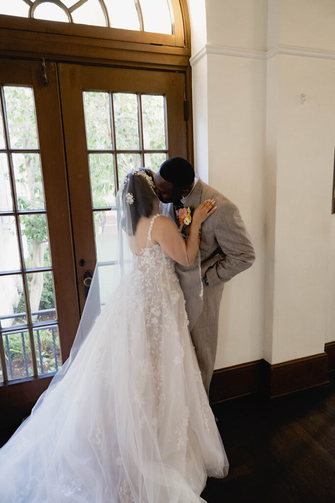 A bride and groom standing together indoors in formal wedding attire.