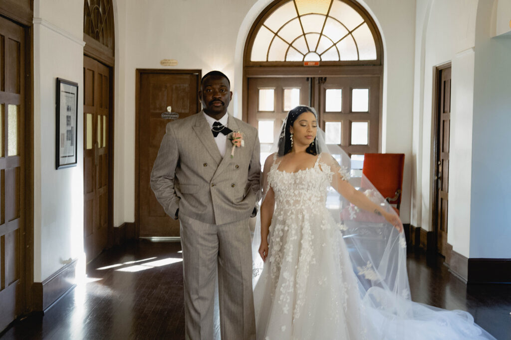 A bride and groom standing together indoors in formal wedding attire.