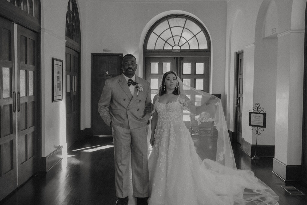 A bride and groom standing together indoors in formal wedding attire.