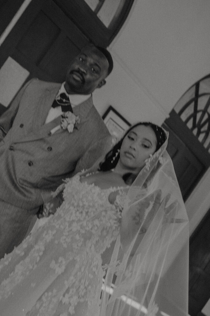 A bride and groom standing together indoors in formal wedding attire.