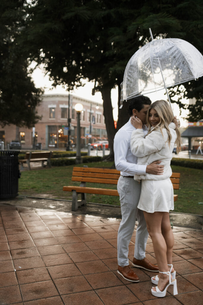 Couple walking through Historic Orange during a rainy engagement session with cinematic, romantic mood