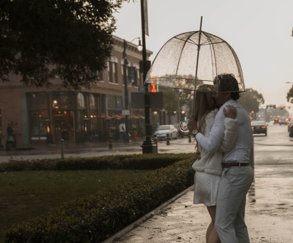 Couple walking through Historic Orange during a rainy engagement session with cinematic, romantic mood