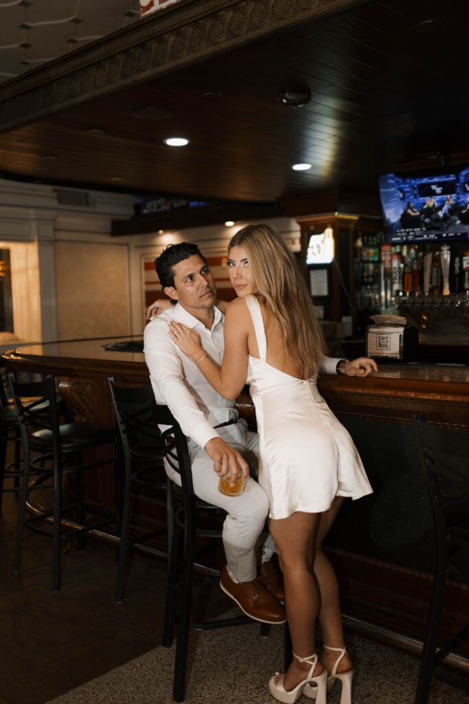 Cinematic engagement photography of couple laughing inside a cozy bar in Historic Orange