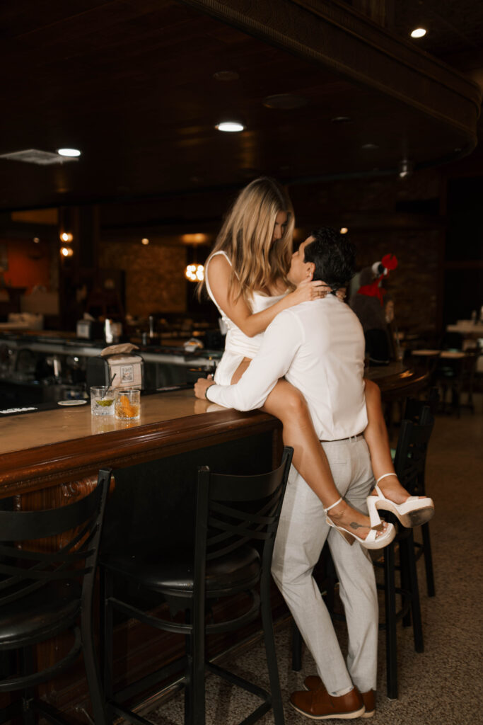 Cinematic engagement photography of couple laughing inside a cozy bar in Historic Orange