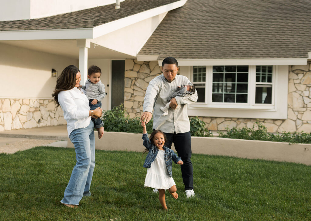 Young family of five standing in front of their forever home during an Orange County in-home family photography session
