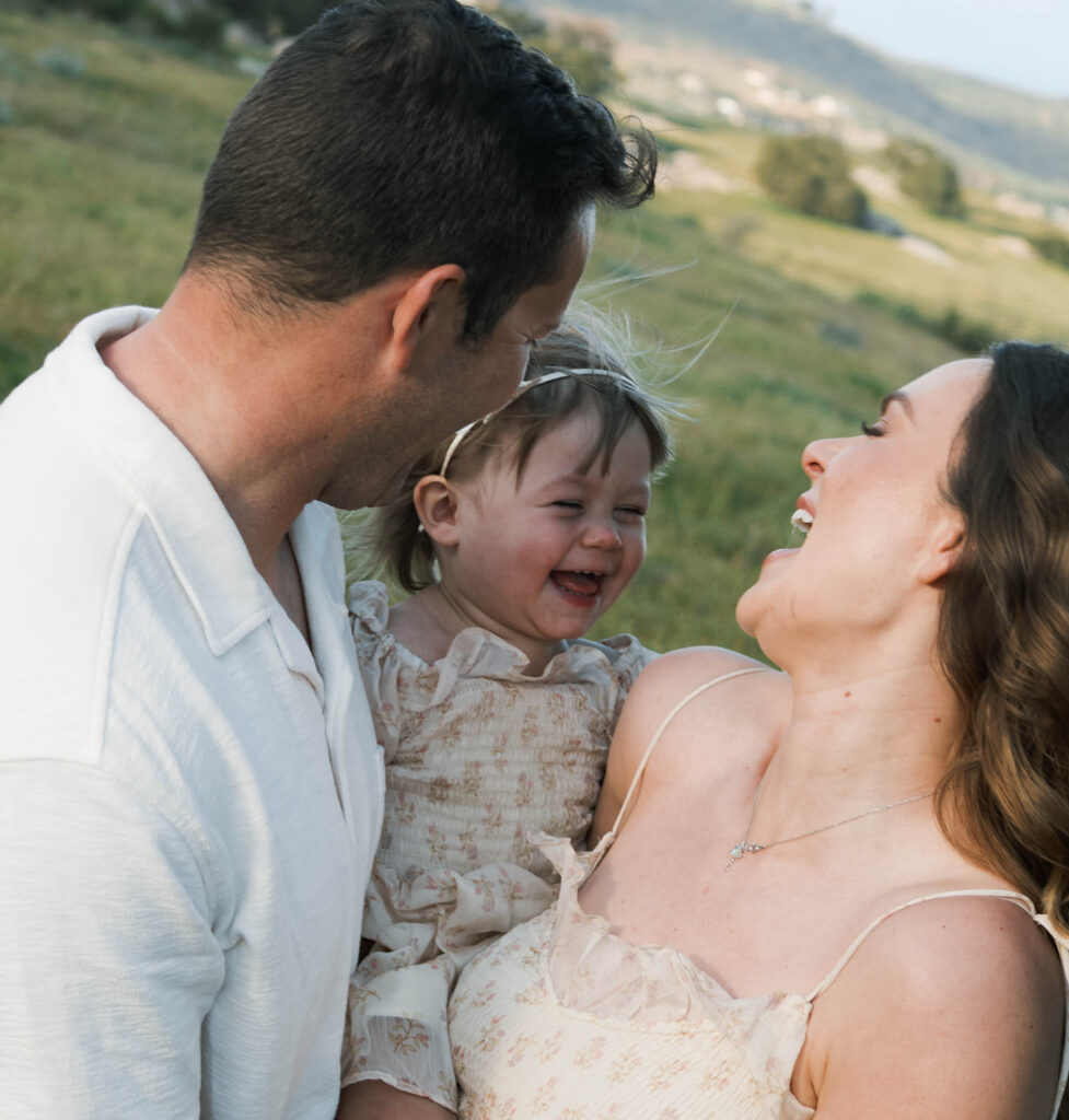 Candid moment of parents and child embracing in golden hour light