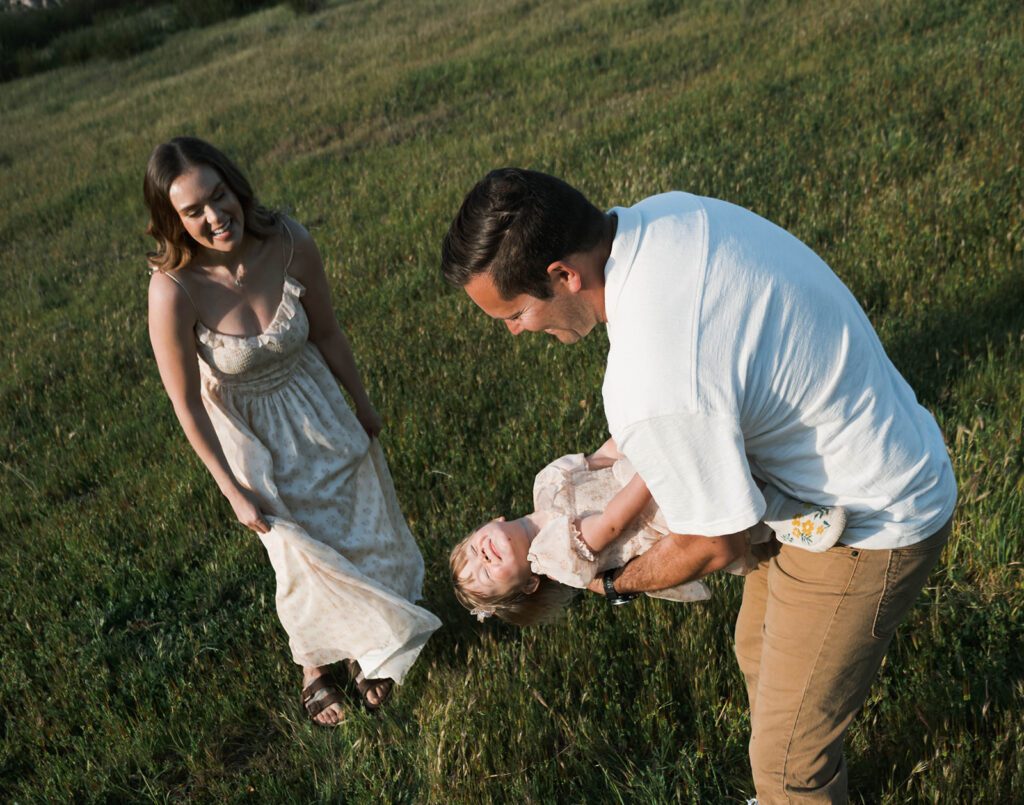 Candid moment of parents and child embracing in golden hour light