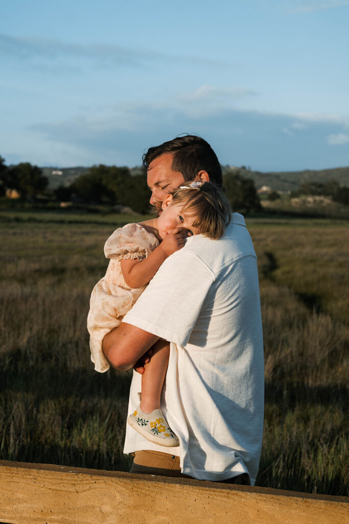 Candid moment of parents and child embracing in golden hour light