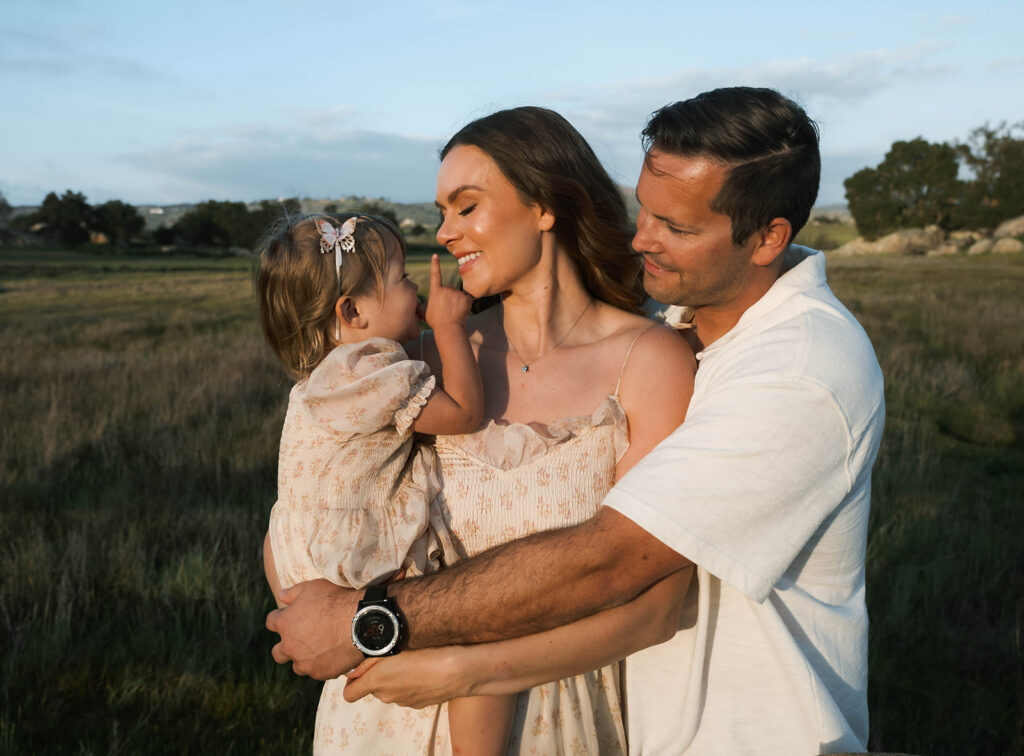 Candid moment of parents and child embracing in golden hour light