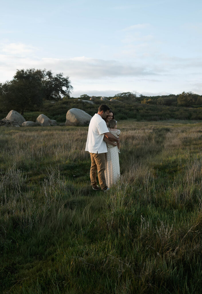Candid moment of parents and child embracing in golden hour light