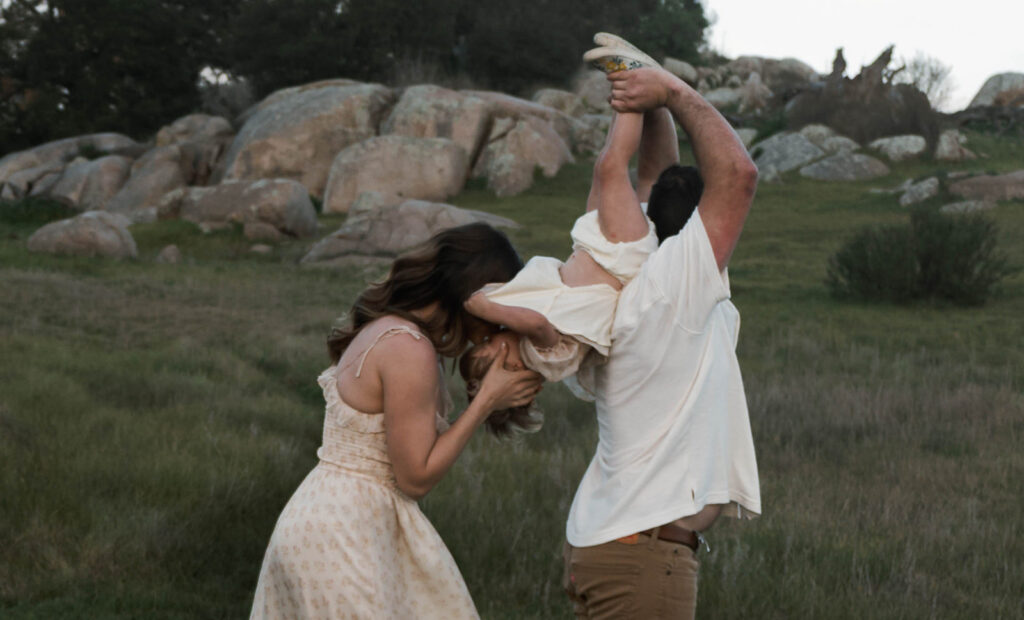 Candid moment of parents and child embracing in golden hour light