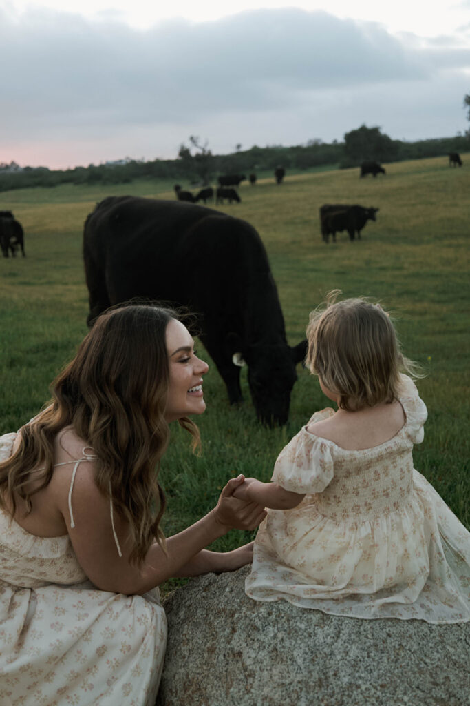 Candid moment of parents and child embracing in golden hour light and cows
