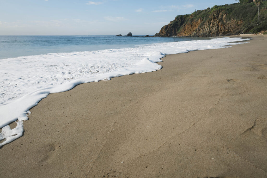 Cinematic film inspired engagement photos in Laguna Beach with Arizona couple in neutral outfits