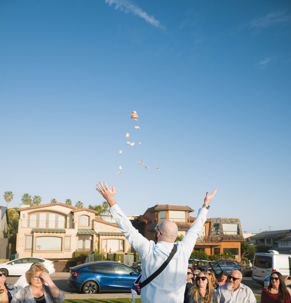 Intimate beach elopement ceremony with family gathered on a cliffside