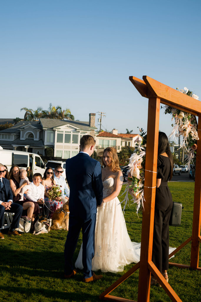 Intimate beach elopement ceremony with family gathered on a cliffside