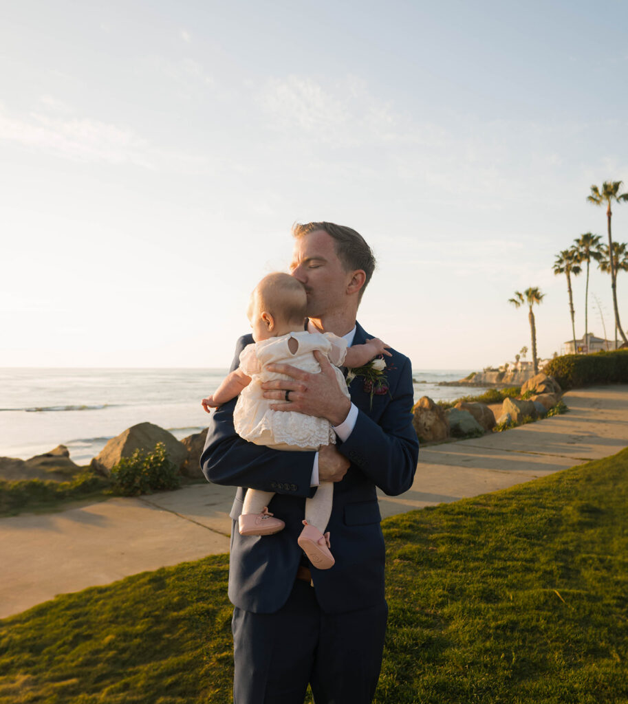 Intimate beach elopement ceremony with family gathered on a cliffside