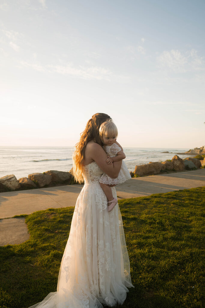 Intimate beach elopement ceremony with family gathered on a cliffside