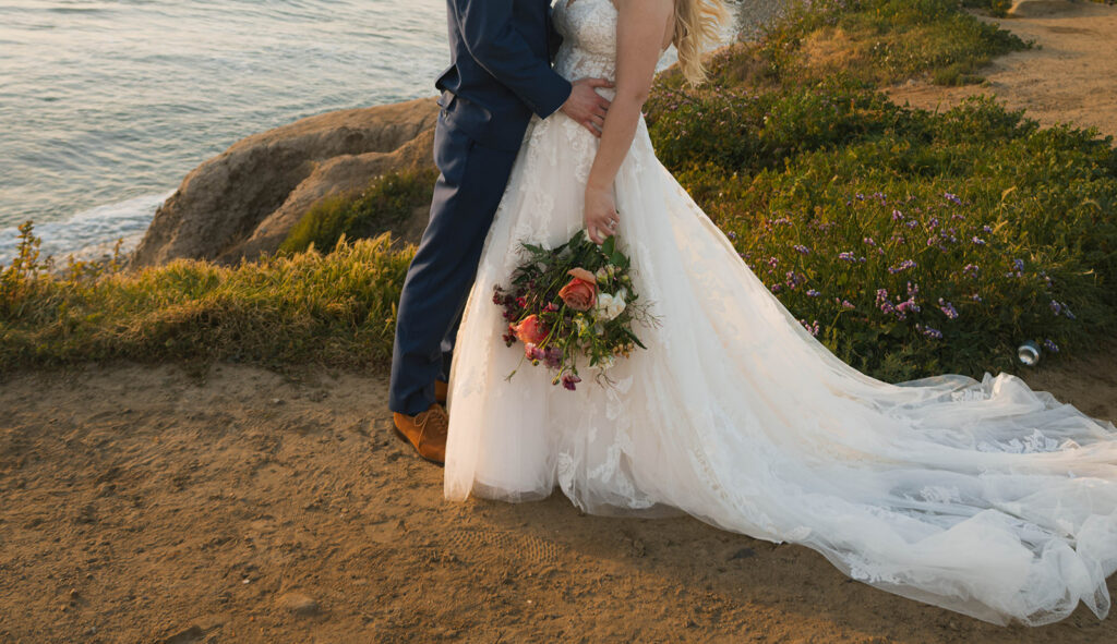 Intimate beach elopement ceremony with family gathered on a cliffside