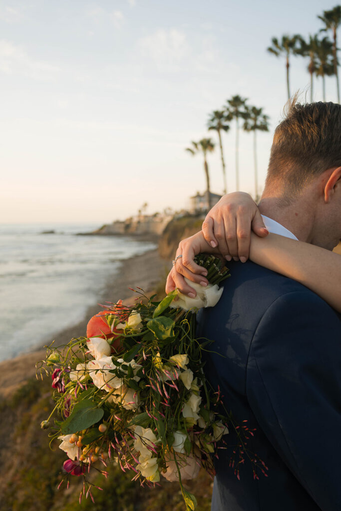Intimate beach elopement ceremony with family gathered on a cliffside