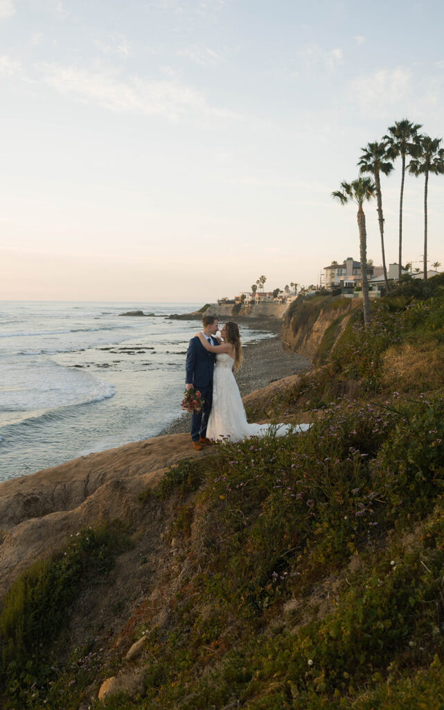 Intimate beach elopement ceremony with family gathered on a cliffside