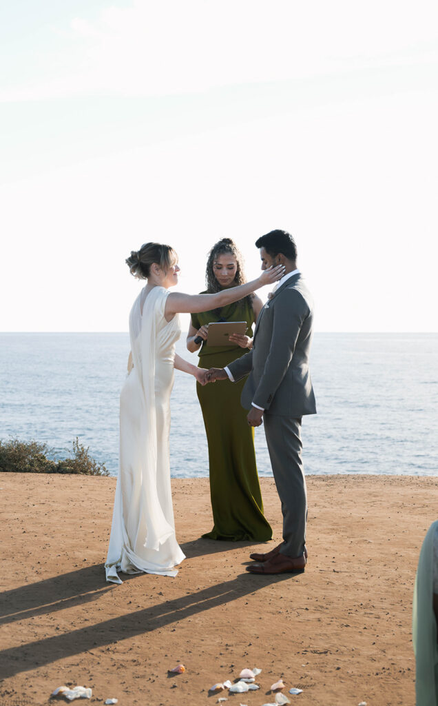 Intimate cliffside elopement ceremony overlooking the ocean at sunset