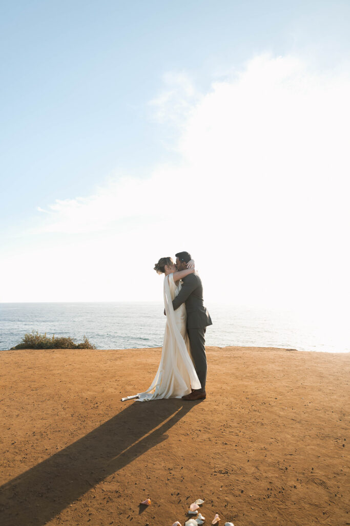 Intimate cliffside elopement ceremony overlooking the ocean at sunset