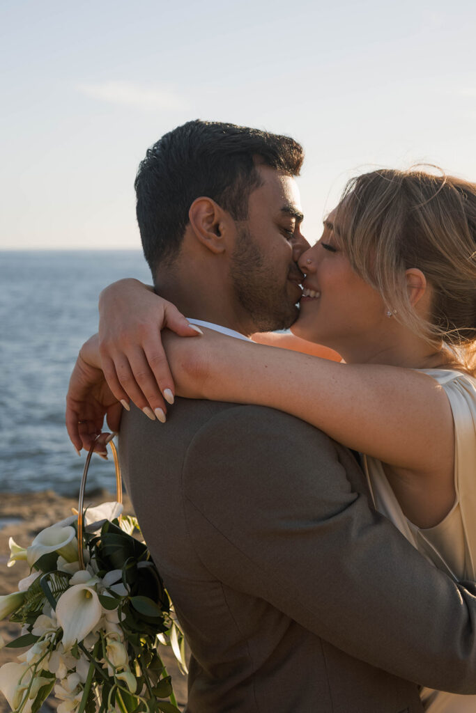 Intimate cliffside elopement ceremony overlooking the ocean at sunset