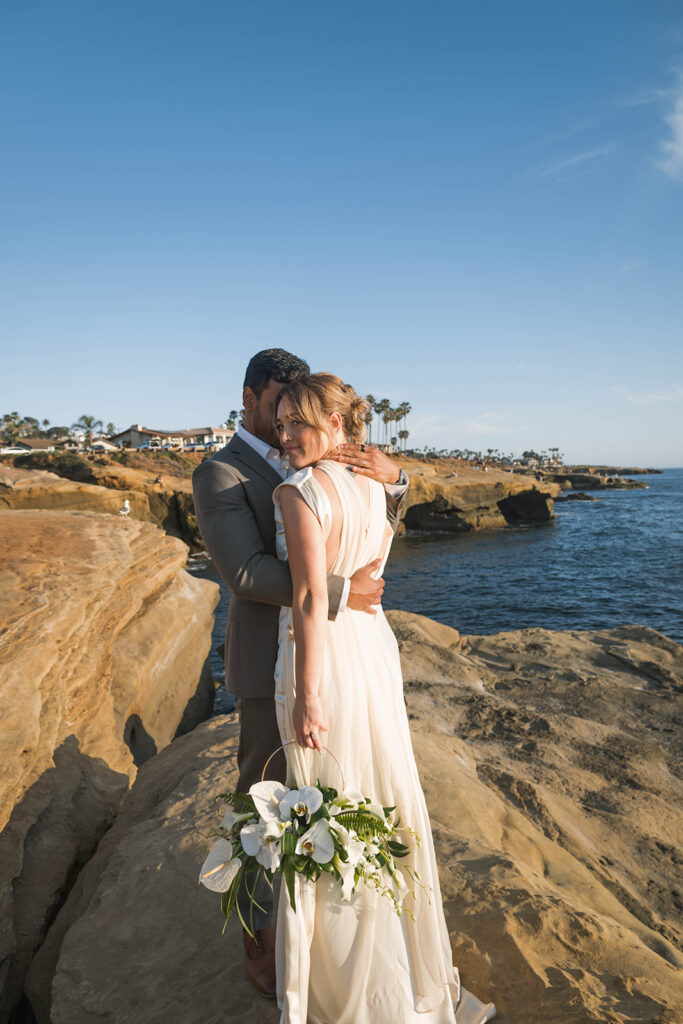 Intimate cliffside elopement ceremony overlooking the ocean at sunset
