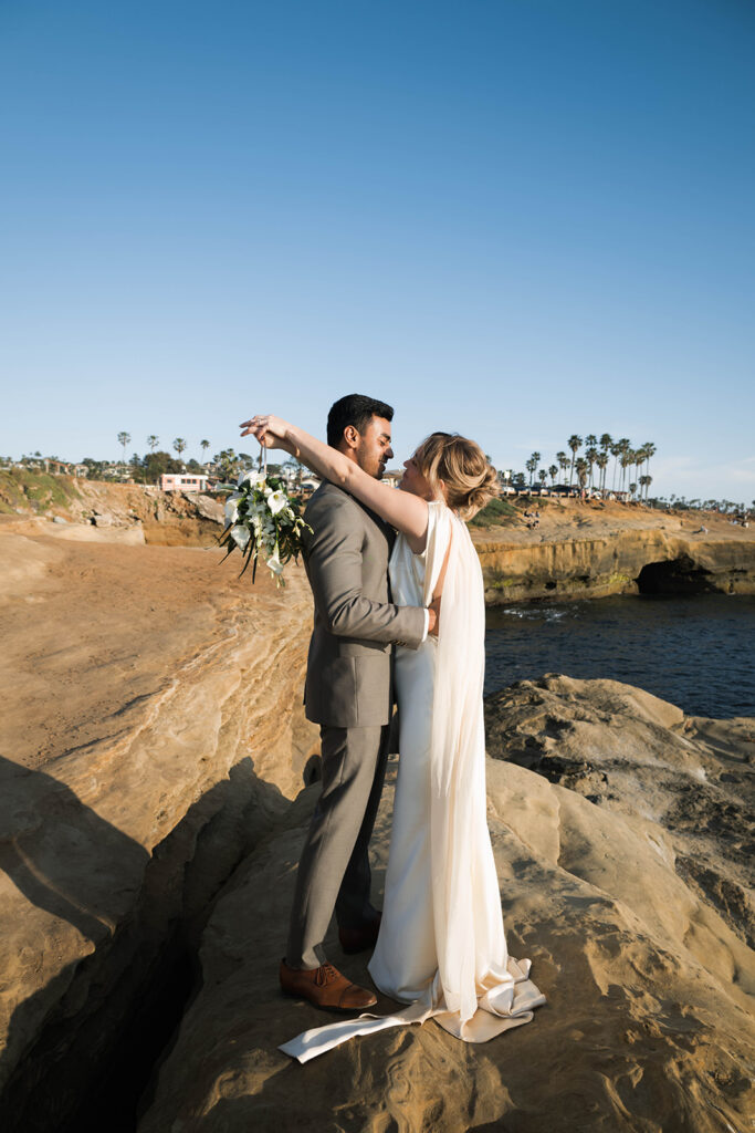 Intimate cliffside elopement ceremony overlooking the ocean at sunset