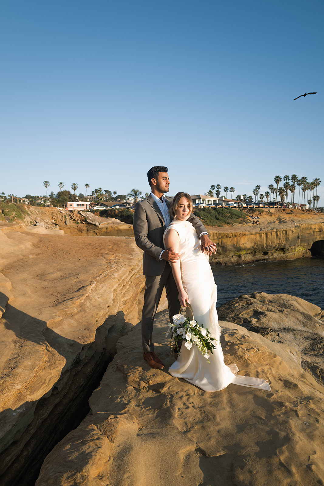 bride and groom editorial pose on a beach cliffside elopement