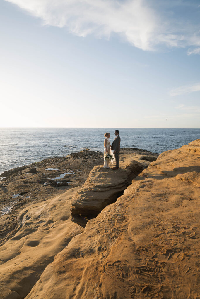 Intimate cliffside elopement ceremony overlooking the ocean at sunset
