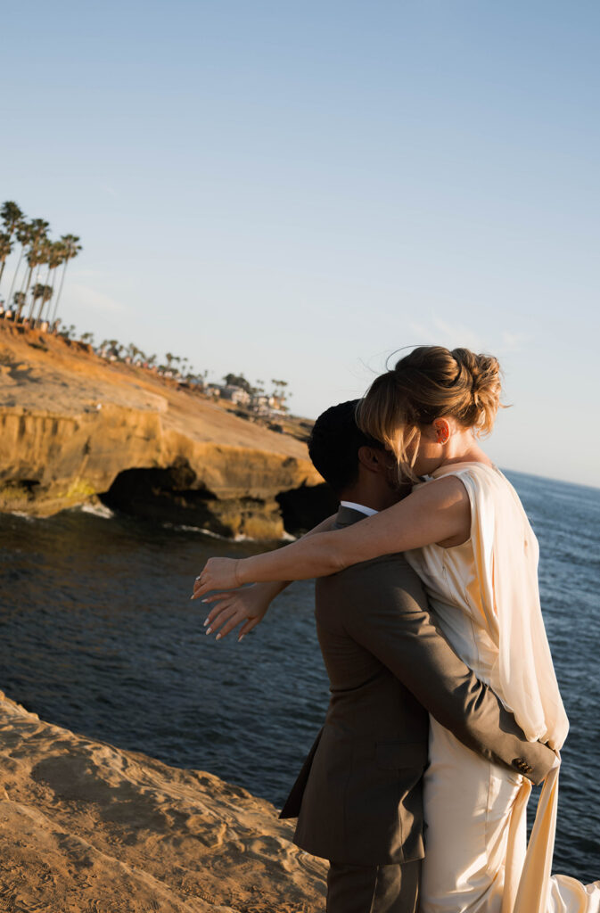 Intimate cliffside elopement ceremony overlooking the ocean at sunset