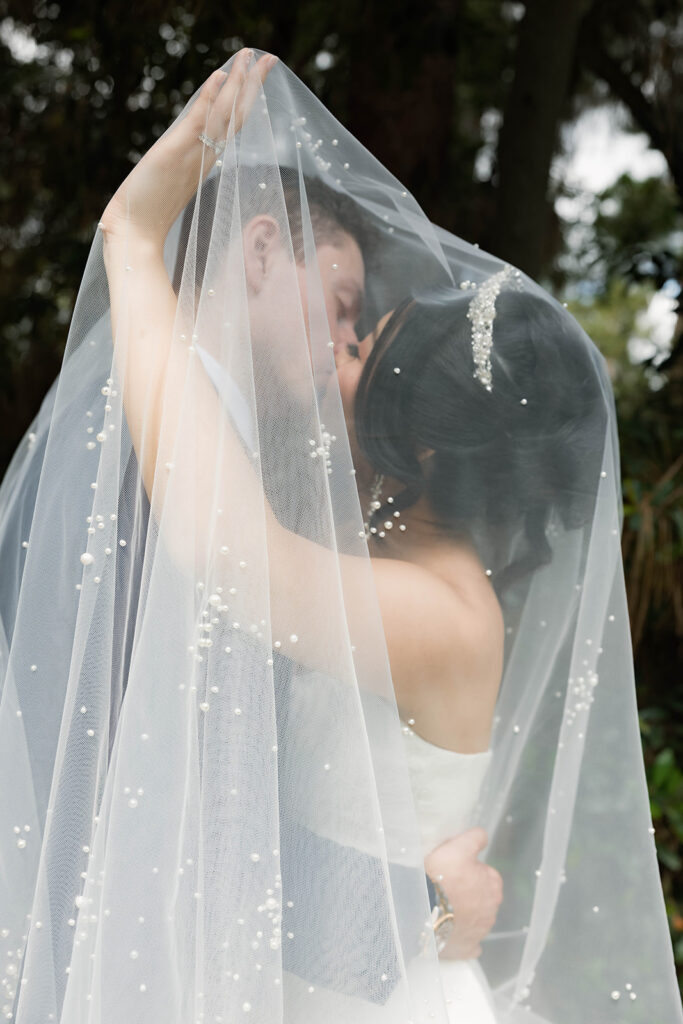 bride and groom kissing under veil